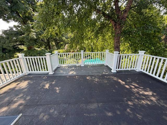 Elevated deck with white railings overlooking a backyard pool